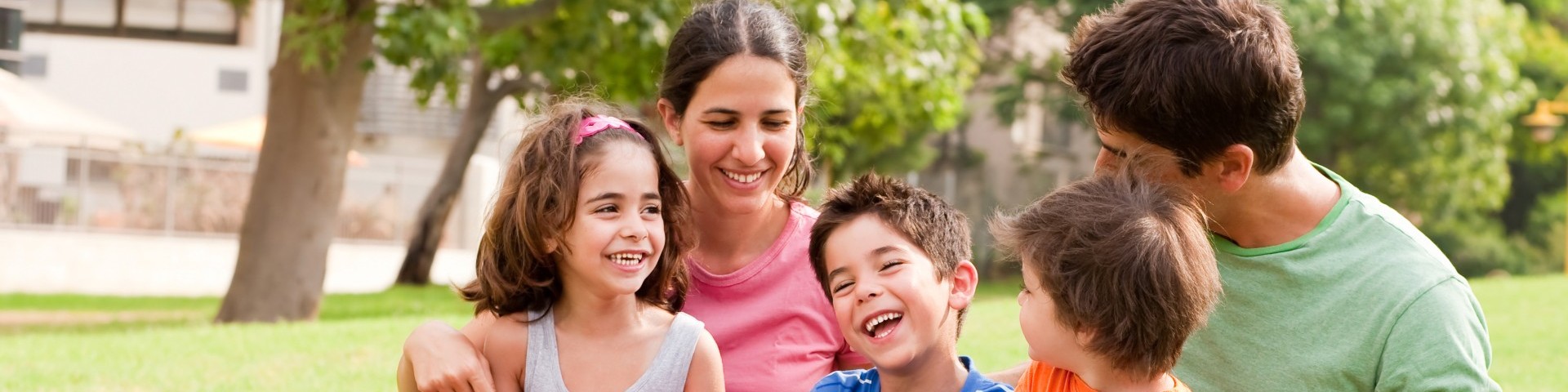 Zwei Erwachsene und Kinder im Park, lachend
