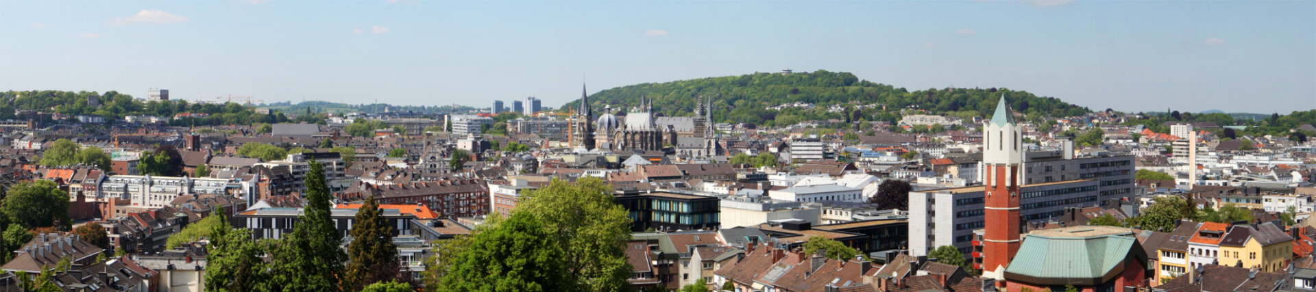 Weitläufige Stadtansicht mit Hügeln, Kirchtürmen und Bebauung