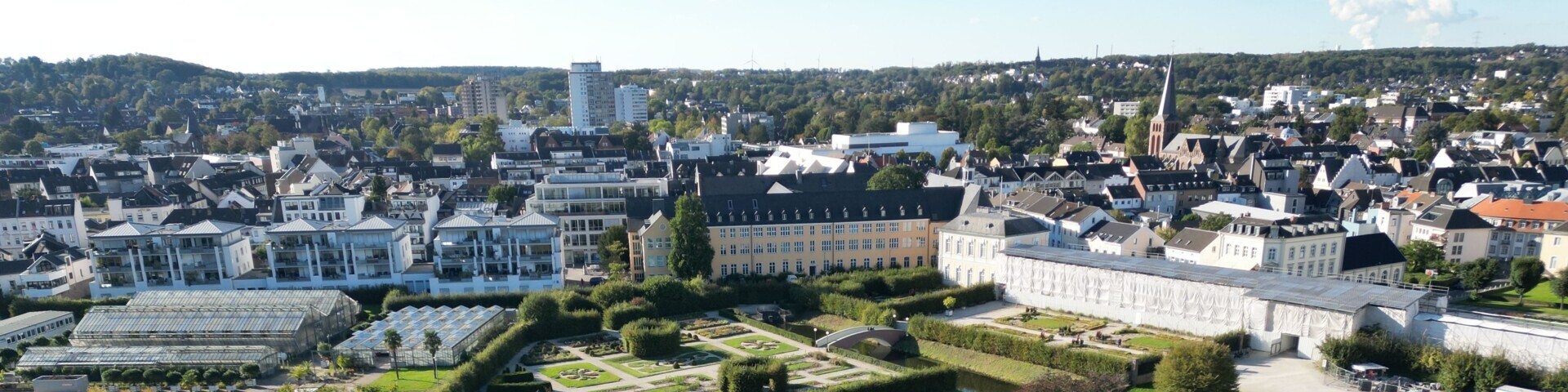 Einige moderne Gebäude und ein Schloss mit einem typischen Schlosspark